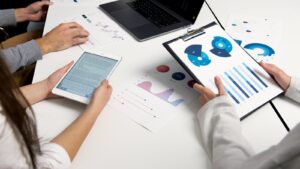 Équipe analysant des graphiques financiers et des rapports numériques lors d'une réunion d'affaires.