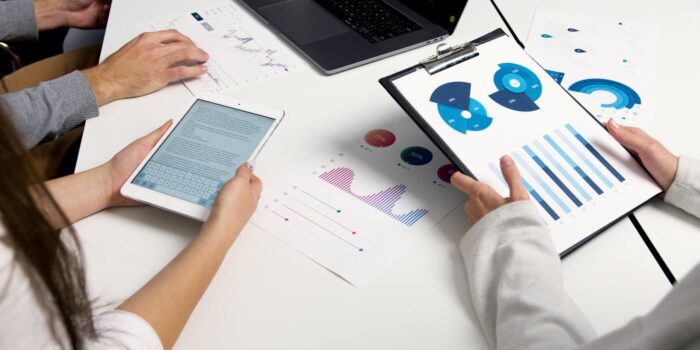 Équipe analysant des graphiques financiers et des rapports numériques lors d'une réunion d'affaires.