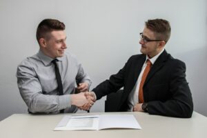 deux hommes se faisant face tout en se serrant la main et en souriant