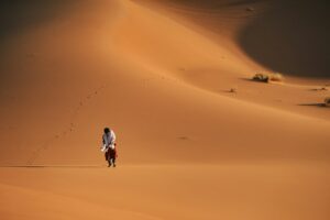 un homme marchant dans un champ de sable dans le désert