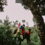 homme en veste rouge assis sur une branche d'arbre