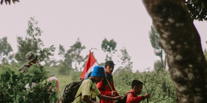 homme en veste rouge assis sur une branche d'arbre